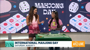 Krizia Cato and host Savannah Louie standing at a mahjong table on the Atlanta News First set during a live International Mahjong Day segment
